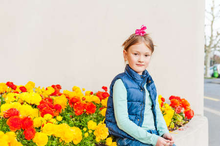 Outdoor portrait of adorable little girl against colorful flowersの写真素材