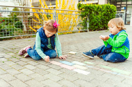 Children playing outdoors on a nice sunny day, drawing with chalkの写真素材