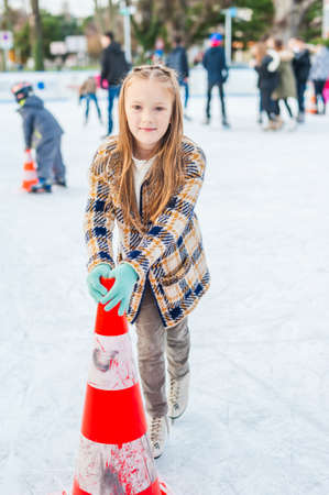 Cute little girl learning to skate with the support on a nice winter dayの写真素材