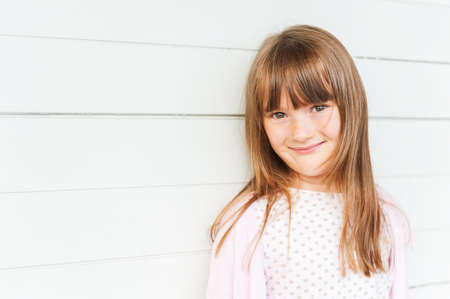 Outdoor portrait of adorable little girl against white wooden background, close upの写真素材