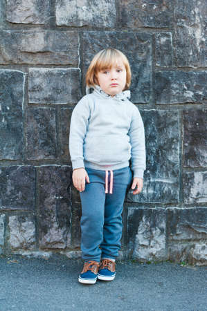 Outdoor portrait of a cute little boy against stone wallの写真素材