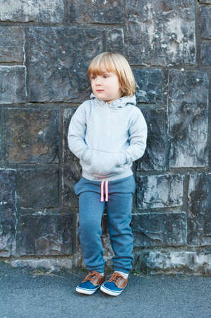 Outdoor portrait of a cute little boy against stone wallの写真素材