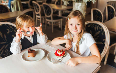 Adorable children eating cakes in a beautiful cafeの写真素材