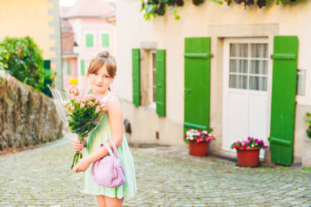 Outdoor portrait of a cute little girl with beautiful bouquet of pink rosesの写真素材