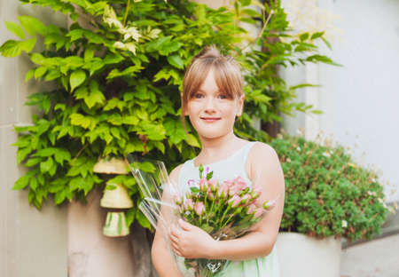 Outdoor portrait of a cute little girl with beautiful bouquet of pink rosesの写真素材
