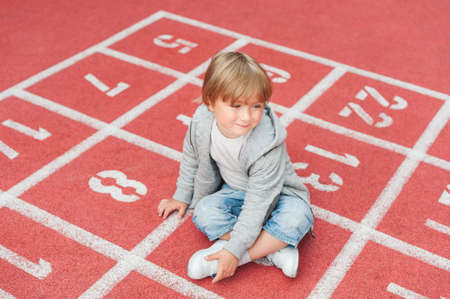 Adorable little boy resting on a schoolyardの写真素材