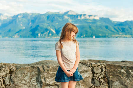 Adorable little girl resting by the lake on a nice warm summer dayの写真素材