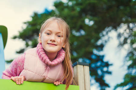 Outdoor portrait of a cute little girl on playground, toned imageの写真素材