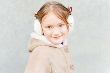 Outdoor portrait of a cute little girl wearing earmuffs and warm coatの写真素材