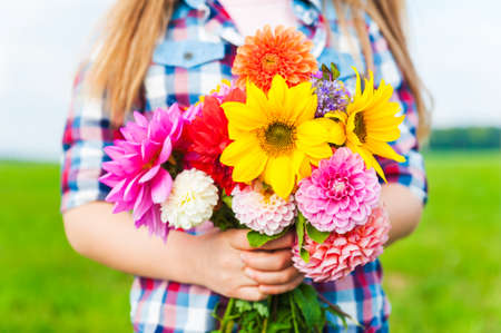 Beautiful bouquet of bright and colorful flowers holding by child\'s handsの写真素材