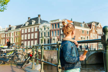 Outdoor portrait of a cute little girl looking on a beautiful canal in Amsterdamの写真素材