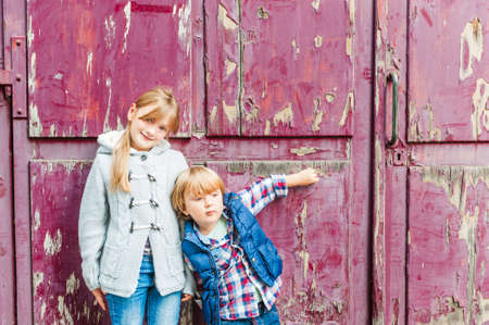 Portrait of two adorable kids outdoors on a street, against old doorの写真素材