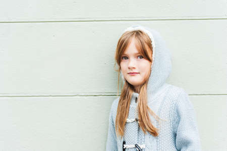 Close up portrait of a cute little girl on a street against wallの写真素材