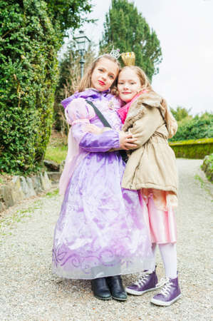 Two little girls friends playing in a park, wearing princess dressesの写真素材