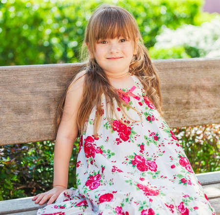 Summer portrait of a cute little girl resting on a bench on a very hot dayの写真素材