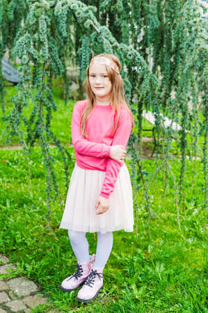 Outdoor portrait of a cute little girl, wearing pink pullover and shiny headbandの写真素材