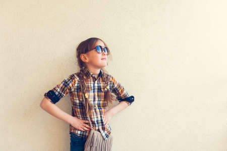 Portrait of a cute little girl wearing yellow and blue plaid shirt and sunglassesの写真素材