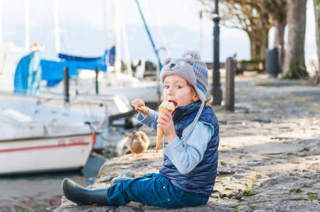 Adorable little boy eating ice cream outdoors on a cold weatherの写真素材