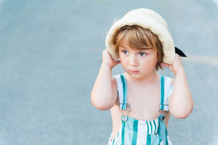 Summer portrait of adorable toddler boy, wearing overalls and hatの写真素材