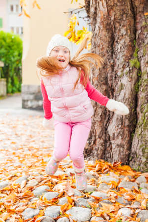 Adorable little girl having fun outdoors on a nice autumn dayの写真素材