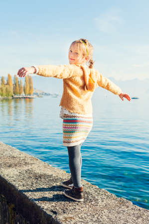 Outdoor portrait of a cute little girl walking next to beautiful lakeの写真素材