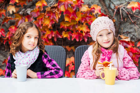 Adorable little girls drinking hot chocolate on a terraceの写真素材