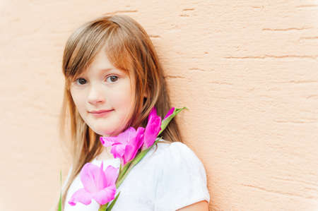 Close up portrait of adorable little girl with a pink flower, outdoorsの写真素材