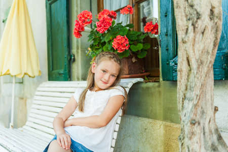 Adorable little girl resting on a bench on a nice warm summer day, outdoorsの写真素材
