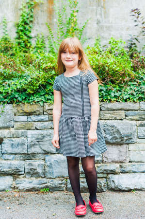 Outdoor portrait of a cute little girl, wearing dress and red shoesの写真素材
