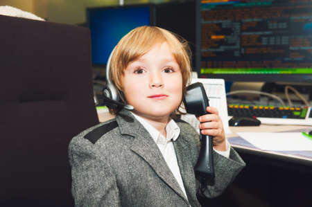 Adorable toddler boy spend the day at his parent\'s work in a trading room at the bank
