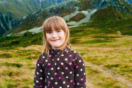 Close up portrait of a cute little girl hiking in mountains, wearing warm fleece jacketの写真素材