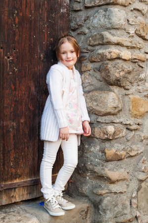 Outdoor portrait of a cute little girl wearing warm white cardigan and jeansの写真素材