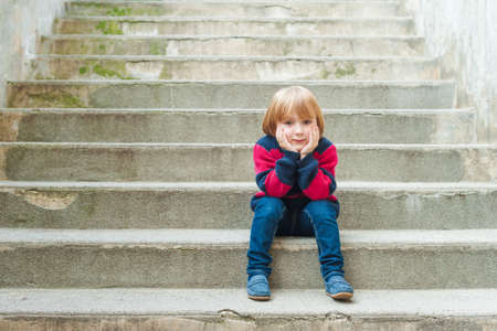 Adorable little boy sitting on stairsの写真素材