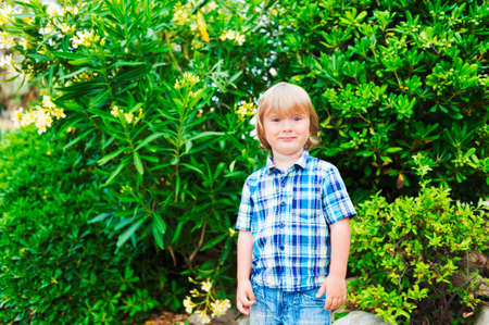 Outdoor portrait of a cute little boy, wearing plaid blue shirt
