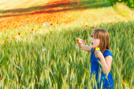 Adorable little girl playing with soap bubbles on a nice summer dayの写真素材