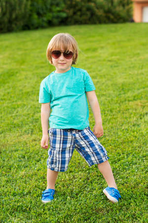 Fashion kid cute little boy wearing turquoise shirt blue shorts and shoesの写真素材