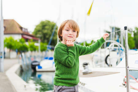 Outdoor portrait of a cute little boy playing by the lake wearing green pulloverの写真素材