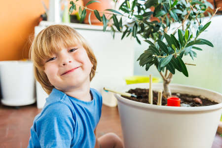 Cute little boy playing with garden tools on the balconyの写真素材