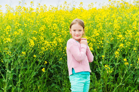 Outdoor portrait of a cute little girl playing with flowers in a countrysideの写真素材