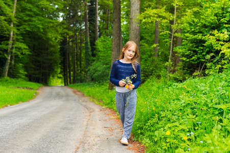 Outdoor portrait of a cute little girl resting in the nature playing with flowersの写真素材