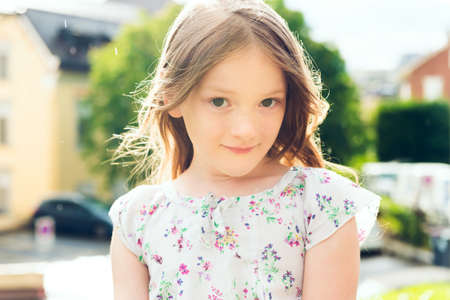 Outdoor close up portrait of a cute little girl under the rain in summertimeの写真素材