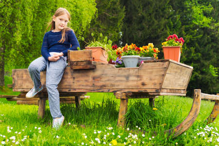 Pretty little girl of 7 years old resting in a countryside sitting on a big slide full of flowersの写真素材