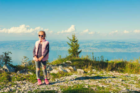 Cute little girl resting on the top of the mountain in french Alps with the view to Switzerland toned imageの写真素材