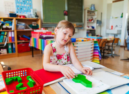 Cute little girl working in a classroomの写真素材