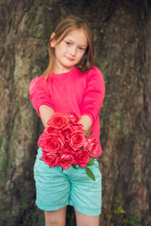 Cute little girl giving beautiful bouquet of bright pink rosesの写真素材