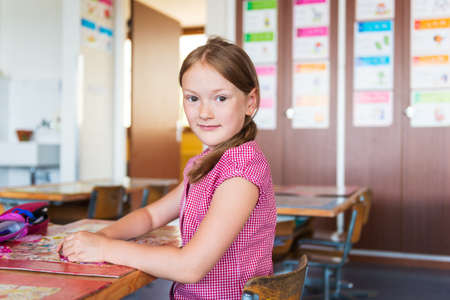 Indoor portrait of a cute little girl in a classroomの写真素材