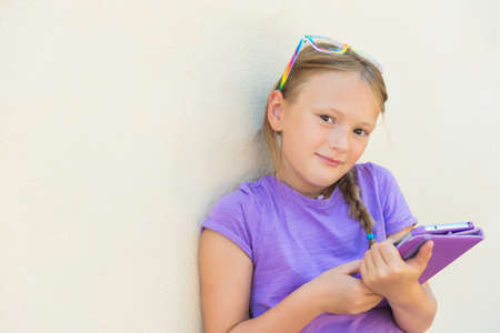 Adorable little girl playing on a digital tablet, wearing rainbow glasses