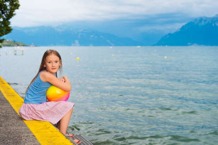Cute little girl resting by the lake at sunsetの写真素材