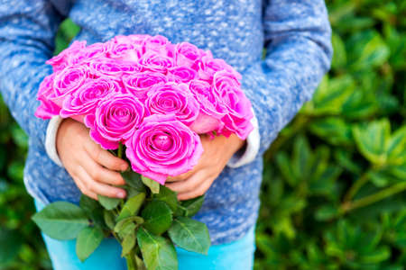 Beautiful bright pink roses in child's handsの写真素材