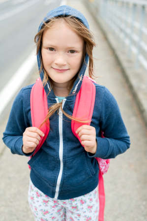 Cute little girl of 7 years walking to school, wearing backpack